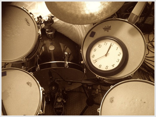 A clock showing midnight, placed on a drum kit